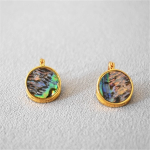 Détail de boucles d'oreilles rondes en laiton plaqué or avec incrustations d'ormeau naturel