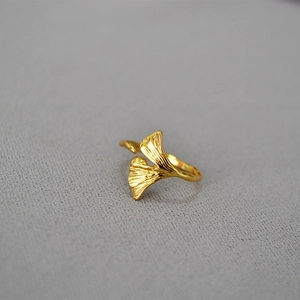 Vintage golden ginkgo leaf open ring with detailed vein textures on a textured gray background