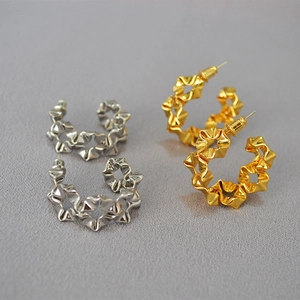 Detailed close-up of C-shaped hoop earrings with irregular metallic pleated texture