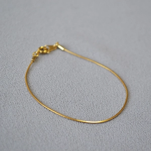Detail of minimalist gold-plated snake chain bracelet featuring a secure lobster clasp