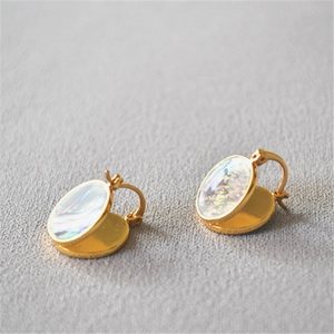 Gros plan sur des boucles d'oreilles en laiton doré avec incrustations d'abalone irisées