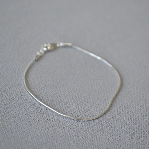Detail of minimalist silver snake bone chain bracelet with secure lobster clasp