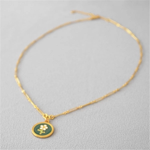 Collier marguerite doré élégant avec pendentif en émail vert sur tissu gris