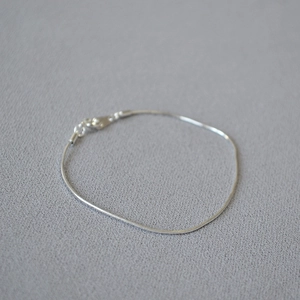 Close-up of a minimalist silver snake chain bracelet with a secure lobster clasp
