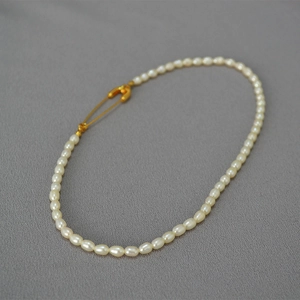 Detail of freshwater rice pearls with a golden safety pin clasp on a minimalist necklace