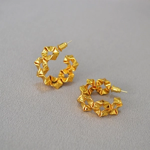 Detailed view of gold geometric wavy earrings with a metallic wrinkled texture surface