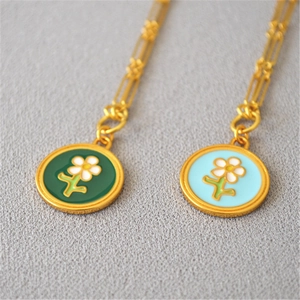 Détail de colliers en émail doré avec pendentifs fleurs vintage en vert et bleu