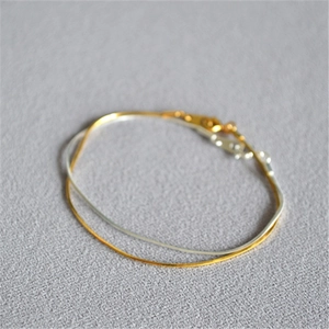 Close-up of minimalist gold and silver snake chain bracelets with lobster clasps