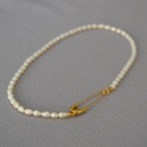 Detailed view of freshwater rice pearl necklace with a golden safety pin lock design