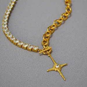 Detail of gold-plated chain necklace with North Star pendant and OT toggle clasp