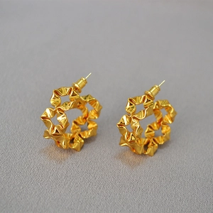 Macro shot of gold floral earrings with unique wrinkled wave texture and C-shaped design