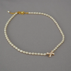 Detail of white enamel butterfly pendant on a freshwater pearl necklace with gold clasp