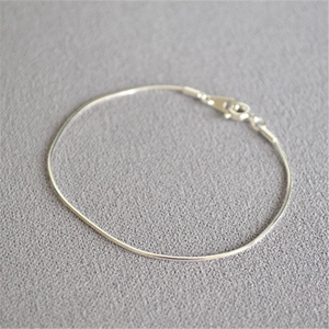 Minimalist silver multifaceted snake chain bracelet with classic spring clasp on grey fabric