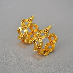 Close-up of gold hollow hoop earrings with unique ruffled texture and 925 silver needles