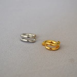 Detail of minimalist gold and silver double-layered ear cuffs with a polished metal finish