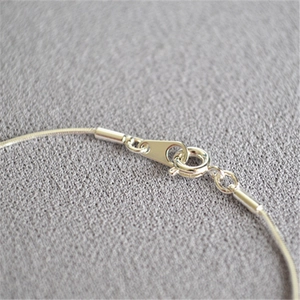 Close-up of the spring clasp and fine silver snake chain texture on a delicate bracelet