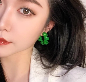 Gros plan d'un modèle portant des boucles d'oreilles spirales vert émeraude brillantes