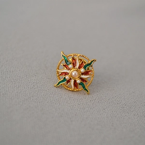 Vue macro d'une broche soleil en émail coloré avec une perle sur tissu gris