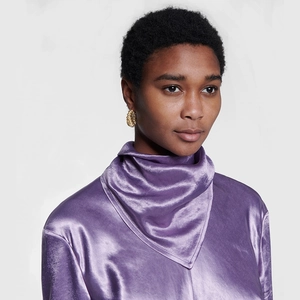 Golden spiral hoop earrings with vintage texture worn on a model with purple satin top