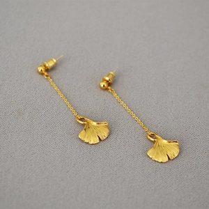 Macro detail of golden ginkgo leaf pendants on elegant drop earrings for women