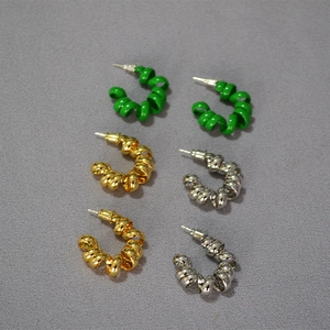 Vue détaillée de boucles d'oreilles spirales en émail vert, doré et argenté