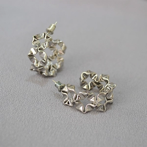 Detailed close-up of silver hollowed wavy flower earrings with unique pleated texture