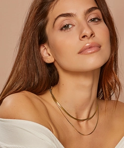 Close-up of double-layer gold snake bone and wave chain necklace on model