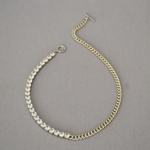 Detail showing gold chain necklace with cubic zirconia links and toggle clasp