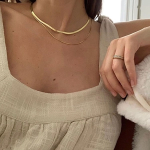 Double-layered gold snake chain necklace set with matching delicate crystal ring on model