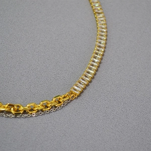 Detailed close-up of mixed gold and silver chains with a rectangular zircon pendant