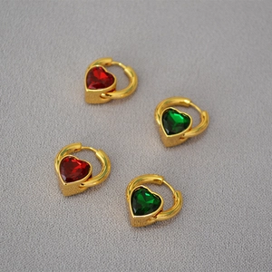 Gros plan de boucles d'oreilles cœur dorées avec cristaux rouges et verts