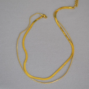 Detail of double-layer gold snake chain with flat blade design and lobster clasp closure