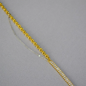 Detail of two-tone chain necklace with square zircon stones on grey fabric background
