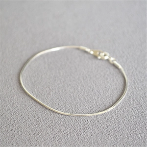 Macro shot of minimalist silver snake chain bracelet featuring a lobster clasp closure