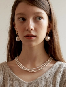 Close-up of elegant triple-layer pearl necklace and large stud earrings on a model