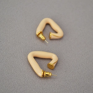 Detail of cream enamel triangle geometric earrings with gold-plated metal accents