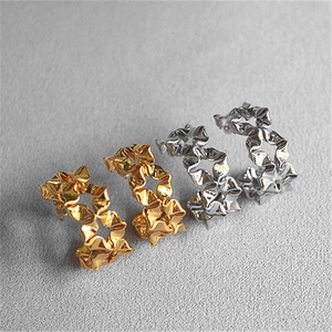 Detail of gold and silver C-shaped earrings with irregular crushed paper texture