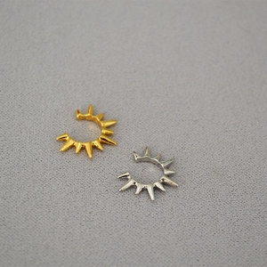 Detail of gold and silver sunburst ear cuffs with a minimalist spiked C-shape design
