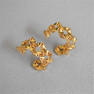 Detailed close-up of golden C-shaped hoop earrings featuring a unique wrinkled metal texture