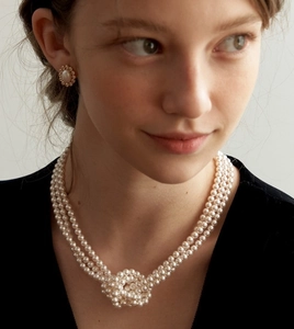Detailed view of layered pearl necklace with a woven pearl knot and matching stud earrings