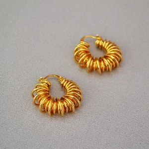 Macro detail of vintage gold-plated brass hoop earrings with spiral coil spring texture