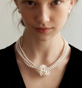 Close-up of triple-layer glass pearl necklace with knotted center and matching earrings