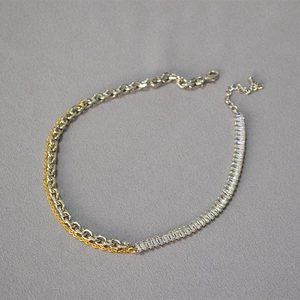 Detail of mixed-metal chain necklace with square zircon stones and lobster clasp closure