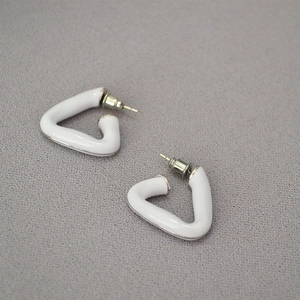 Close-up of white enamel triangular hoop earrings with 18k gold plated brass finish