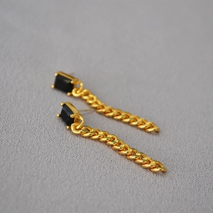 Detail of vintage gold plated earrings with emerald green stone and cuban chain drop