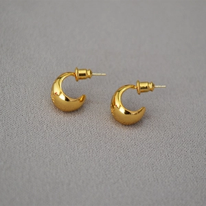 Polished golden crescent-shaped earrings with minimalist design on textured grey background
