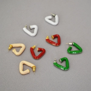 Detail of four colorful enamel geometric stud earrings in white, red, green, and beige