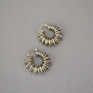 Detailed close-up of silver spiral spring hoop earrings on textured fabric background
