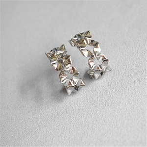 Macro shot of silver hollow crinkle flower earrings with irregular wavy metal texture