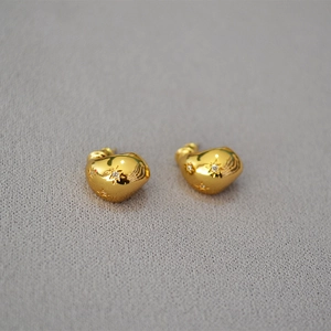 Macro shot of irregular golden stud earrings with zircon stars on gray fabric